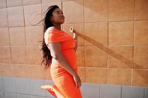 modelo de mulher afro-americana xxl em vestido laranja. foto