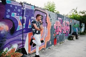 retrato de estilo de vida de homem bonito posando na rua da cidade com parede de graffiti. foto