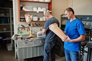 dois trabalhadores de homem protético fazendo perna protética enquanto trabalhava no laboratório. foto