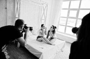 a equipe de dois fotógrafos fotografando garotas gêmeas de estúdio enquanto elas fazem seu próprio creme de máscaras. fotógrafo profissional no trabalho. foto