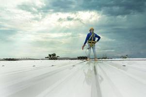 trabalhador da construção civil em roupas de trabalho instalando novas ferramentas para telhados ferramentas para telhados, furadeira elétrica e uso em novos telhados de madeira com chapas de metal. foto