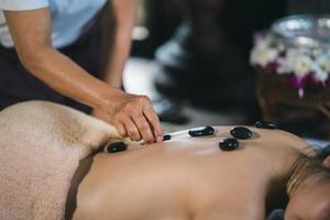 massagem e spa tratamento relaxante da síndrome do escritório usando o estilo tradicional de massagem tailandesa com pedras quentes. asain massagista feminina fazendo massagem trata dor nas costas, dor no braço, estresse para mulher cansada do trabalho. foto