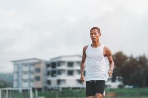 atleta esportista corredor treinamento executado na pista no estádio de manhã. homem corredor vestindo colete branco para praticar corrida prepare-se para corrida de competição. conceito de esporte. foto