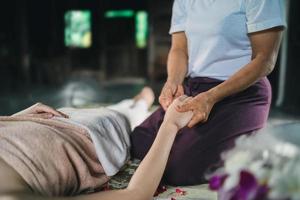 massagem e spa tratamento relaxante da síndrome do escritório usando o estilo tradicional de massagem tailandesa com pedras quentes. asain massagista feminina fazendo massagem nas mãos trata o estresse para a mulher. foto