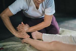 massagem e spa tratamento relaxante da síndrome do escritório usando o estilo tradicional de massagem tailandesa com pedras quentes. asain massagista feminina fazendo massagem nos pés trata o estresse para a mulher. foto