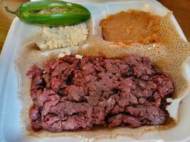 comida etíope kitfo carne crua e pão injera foto