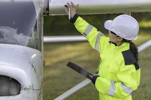 técnico consertando o motor do avião, engenharia aeroespacial feminina verificando motores de aeronaves, manutenção mecânica asiática inspeciona motor de avião foto