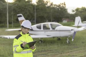 técnico consertando o motor do avião, engenharia aeroespacial feminina verificando motores de aeronaves, manutenção mecânica asiática inspeciona motor de avião foto