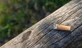 única ponta de cigarro em uma placa de madeira foto