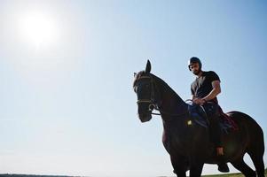 homem de barba alta árabe usar capacete preto, cavalgar cavalo árabe. foto