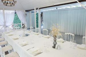 salão de banquetes vazio pronto para receber convidados no terraço de verão. mesa festiva branca foto