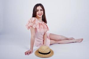 retrato de uma mulher elegante de vestido rosa sentado e posando com um chapéu no chão do estúdio. foto