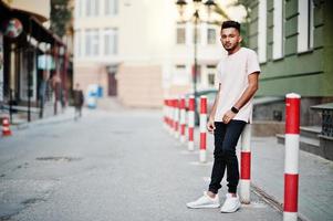 homem de barba indiana elegante na camiseta rosa. modelo da índia posou ao ar livre nas ruas da cidade. foto