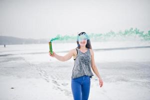 jovem com bomba de fumaça de cor verde na mão em dia de inverno. foto