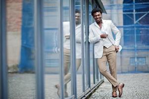 pensativo jovem cavalheiro afro-americano bonito em trajes formais. homem preto elegante modelo de casaco branco. foto