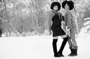 duas mulheres afro-americanas de cabelo encaracolado usam suéteres posados no dia de inverno. foto