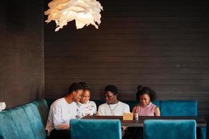 amigos africanos felizes sentados e conversando no café. grupo de negros reunidos em restaurante. foto