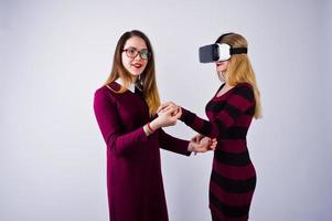 duas garotas de vestidos roxos experimentando óculos de realidade virtual no estúdio. foto