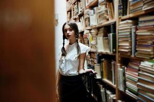 menina com tranças na blusa branca na antiga biblioteca. foto