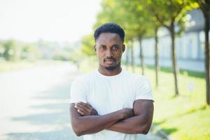 jovem atleta masculino americano africano, na aula de fitness, olhando para a câmera com cruzado foto