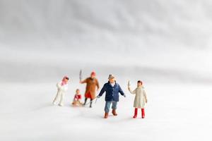 pessoas em miniatura família feliz andam de trenó com fundo de neve foto