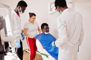 equipe de médicos multirraciais. médicos do sexo masculino afro-americanos com uma mulher de médico caucasiano. profissional de uniforme tirando raio-x do paciente. foto