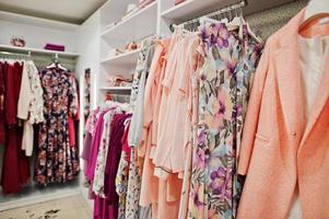 conjunto de roupas coloridas de pêssego feminino nas prateleiras na loja de roupas nova boutique moderna. coleções de vestidos de primavera verão. foto