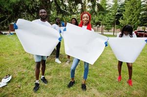 grupo de voluntários africanos felizes segura uma placa em branco vazia no parque. áfrica voluntariado, caridade, pessoas e conceito de ecologia. espaço livre para o seu texto. foto