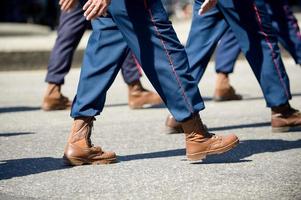 militares marchando em uma rua. pernas e sapatos em linha foto