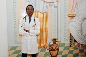 elegante médico afro-americano com estetoscópio posado no interior. foto