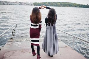 retrato de duas belas jovens indianas ou adolescentes do sul da Ásia no vestido mostram o coração pelas mãos. foto