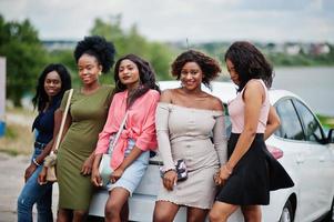 grupo de cinco garotas afro-americanas felizes posaram contra o carro. foto