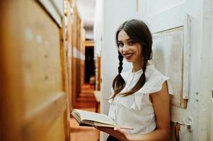 menina com tranças na blusa branca na antiga biblioteca. foto