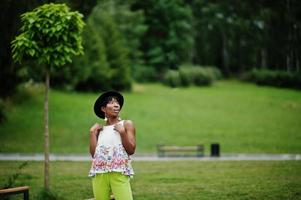 incrível mulher modelo americano africano em calças verdes e chapéu preto posou no parque. foto