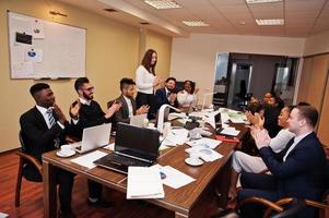 reunião de equipe de negócios multirracial ao redor da mesa da diretoria, bater palmas. foto