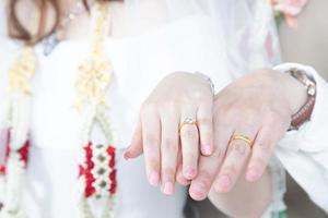close-up mão noivo casal amantes mostrar usar o anel de casamento na noiva de mãos dadas juntos na cama polvilhe pétalas de rosa representa romântico. propor para se casar, casamento e conceito de amor. foto