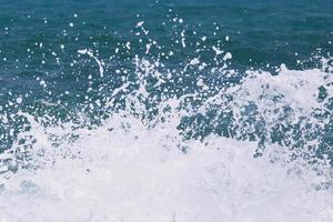 ondas do mar na onda do mar espirrando água da ondulação. fundo de água azul. deixe espaço para escrever um texto descritivo. foto