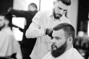 homem barbudo bonito na barbearia, barbeiro no trabalho. foto