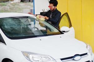 homem do sul da Ásia ou homem indiano lavando seu transporte branco na lavagem de carros. foto