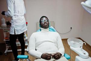 paciente de homem afro-americano na cadeira odontológica. consultório de dentista e conceito de prática médica. foto