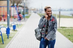 jovem afro-americana milenar na cidade. mulher negra feliz com fones de ouvido sem fio. conceito de geração z. foto