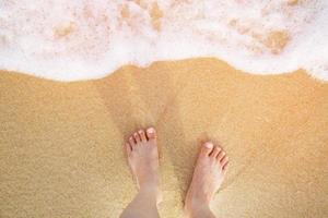 close-up dos pés descalços de um homem molhado na praia, com uma borda de areia suavemente abaixo deles. férias na praia oceânica, pé na areia do mar. deixe espaço de cópia vazio digite o texto acima. conceito de viagem. foto