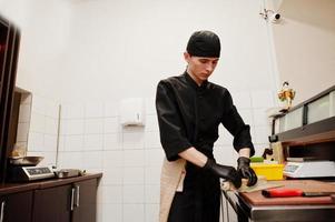 chef profissional veste de preto fazendo sushi e pãezinhos em uma cozinha de restaurante de comida tradicional japonesa. foto