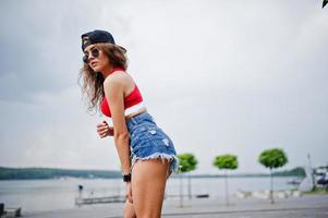 garota modelo sexy no top vermelho, shorts jeans mostram suas nádegas. foto