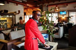 moda homem afro-americano modelo dj no terno vermelho com controlador de dj. foto