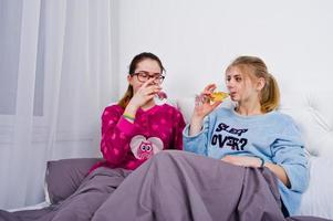 duas amigas garotas de pijama se divertindo na cama no quarto. foto