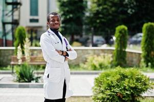 médico americano africano masculino no jaleco com estetoscópio ao ar livre.
