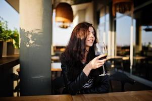 jovem mulher encaracolada desfrutando de seu vinho em um bar. foto