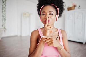 jovem afro-americana ouve música em fones de ouvido no quarto dela. foto