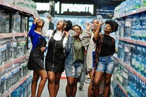 grupo de cinco mulheres africanas com garrafas plásticas de água no supermercado. foto